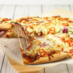 Ciepły, ciągnący się ser na kawałku pizzy z warzywami. Idealny spód do pizzy zachęca do sięgnięcia po kolejny kawałek.