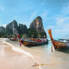 Bateaux traditionnels sur une plage de sable fin, parfaits pour organiser son voyage en Thaïlande et explorer les îles.