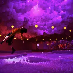 A person in a yellow shirt leaps into a ball pit at the balloon museum London, surrounded by purple clouds and yellow lights.