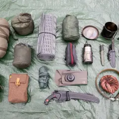 Outdoor-Ausrüstung: Schlafsack, Isomatte, Messer, Kochgeschirr, Handschuhe, Taschen und eine bpa-freie Trinkflasche.