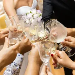 Radosny toast podczas polskiego ślubu. Dłonie trzymają kieliszki z szampanem, tworząc symbol jedności i świętowania.
