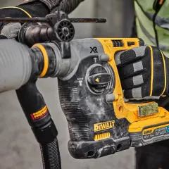 Main d'un ouvrier tenant un marteau-piqueur DeWalt origine, prêt à travailler sur un chantier.