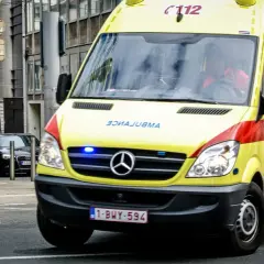 Ambulance jaune, véhicule prioritaire, roule en ville. Les gyrophares bleus clignotent.
