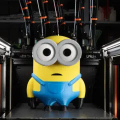 Minion wydrukowany na dobra drukarka 3d. Maszyna z wieloma głowicami i szpulami filamentu w tle.