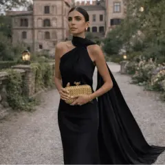 Kvinna i elegant svart klänning med släp, perfekt för black tie dress code women. Hon håller en guldig clutch.