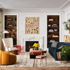 A living room showcasing how to mix modern and vintage decor with a plush yellow armchair, ornate mirror, and a marble fireplace.