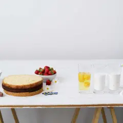 Tårtbotten Camilla Hamid förbereds med jordgubbar, grädde, ägg, mjölk och mjöl. Svenska flaggor antyder firande.