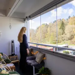 En kvinna njuter av utsikten från en mysig balkong med fin balkong inredning. Vårens färger syns i träden.