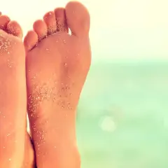 Stopy z piaskiem na plaży, z widocznym płaskostopiem.