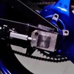 Mecanismo de ajuste para cadena destensada moto, con actuador lineal y soporte metálico sobre basculante azul.
