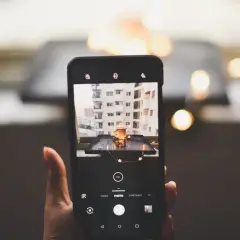 Smartfon robi zdjęcie kubka z napojem i światełek. To przykład fotografii produktowej.