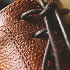 Gros plan sur le cuir texturé d'une chaussure marron, avec des lacets sombres. Un peu de cirage pour chaussures pourrait lui redonner tout son éclat.