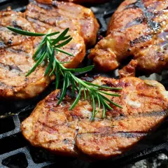 Soczyste plastry karkówki, idealnie przypieczone na grillu, z gałązką rozmarynu. To efekt doskonałej marynaty do karkówki.