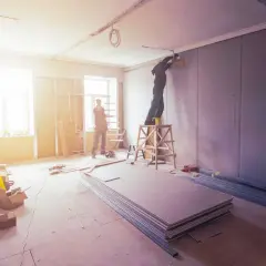 Lavori in corso: operai installano cartongesso. Per sapere quanto costa smaltire il cartongesso, informati sui costi di smaltimento dei materiali edili.