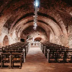 Historische Gewölbe des Kulturvereins Glems, bereit für eine Zeremonie mit Reihen von Holzstühlen und einem festlichen Altar.