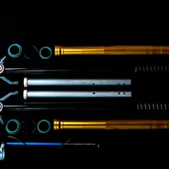 Dos horquillas telescópicas de moto doradas y plateadas, con resortes y juntas, listas para el montaje.