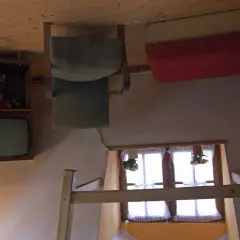 Wnętrze domu do góry nogami w Szymbarku: odwrócony telewizor, krzesło i łóżko.
