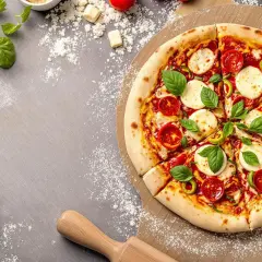 Une délicieuse pizza Margherita, fraîchement sortie du four, sur une planche à pizza. La pâte à pizza est dorée et garnie de tomates, mozzarella et basilic.