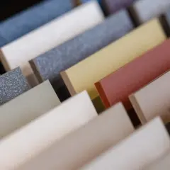 Reihen von farbigen Mustern aus Faserzement, die verschiedene Texturen und Töne zeigen, von Grau bis Rosa.