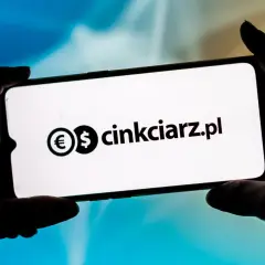 Dłonie trzymają smartfon z widocznym logo i nazwą "cinkciarz.pl". To portal, który ułatwia wymianę walut, jak Conotoxia.