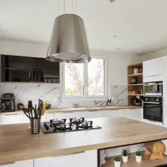 Cuisine moderne avec îlot central en bois, hotte design en alliage inox, et électroménagers intégrés.