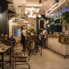 Gente disfrutando de tapas en Almería, con camareros sirviendo y un ambiente acogedor.