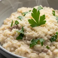 Un cremoso risotto ai funghi, mantecato con parmigiano e guarnito con prezzemolo fresco. Un piatto di riso in cagnone che profuma di casa.