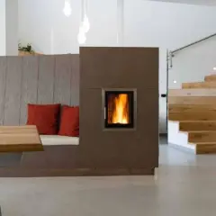 Moderner Wohnraum mit gemütlicher Sitzbank, Kamin und Holztreppe. Die Pelletheizung im Kamin sorgt für Wärme, die Vorschriften sind eingehalten.