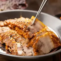 Plasterki soczystej wieprzowiny, posypane czarnym sezamem, idealne na dietę samo mięso. Obok widać kimchi.