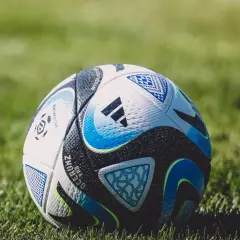 Piłka nożna na zielonej trawie, z widocznymi detalami i logo Adidas.