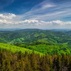 Widok na zielone wzgórza Beskidu Śląskiego, gdzie w oddali majaczą trzy kopce wiślańskie.