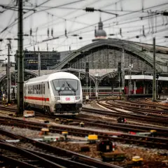 Pociąg DB na stacji, skomplikowana sieć torów i trakcji elektrycznej. Widoczna blokada liniowa sygnalizuje gotowość do odjazdu.