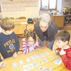 Lehrerin erklärt Kindern beim Projekttag Grundschule ein Kartenspiel.
