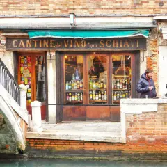 Cantina del Vino, un posto ideale per mangiare a Venezia spendendo poco. Coppia parla davanti al locale pieno di bottiglie.