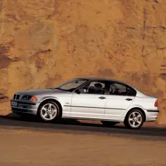 Srebrne bmw e46 330i sunie po drodze na tle skalistego, pomarańczowego zbocza.