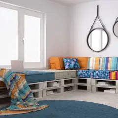 Divano con pallet, colorato e accogliente, con cuscini vivaci e una coperta morbida. Perfetto per un angolo relax.