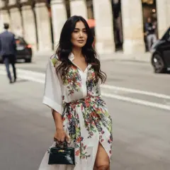 Mujer con vestido estampado floral, estilo manga francesa, pasea por París con un bolso verde.
