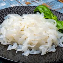 Makaron konjac na czarnym talerzu, z listkiem bazylii. To zdrowa alternatywa dla tradycyjnych klusek.