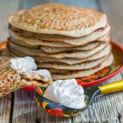 Pile de crêpes épaisses alsaciennes, garnies de crème fraîche. Une cuillère décorée en est aussi remplie.