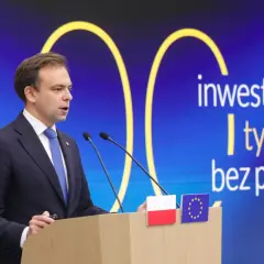 Mężczyzna w garniturze przemawia za mównicą. Na ekranie za nim napis: "inwestycje do tysięcy zł bez podatku".