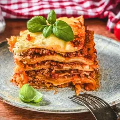 Ein Stück Lasagne Bolognese, ein authentisches lasagne rezept original italienisch, garniert mit Basilikum.
