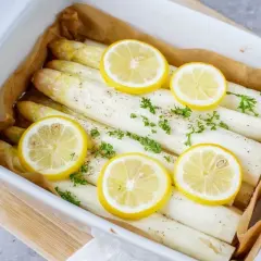 Frischer weißer Spargel im Backofen mit Zitronenscheiben und Petersilie, bereit zum Genießen.