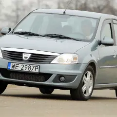 Szary Dacia Logan sedan z polskimi tablicami WE 2987P jedzie po drodze.