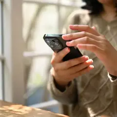 Dłonie kobiety trzymają smartfon, korzystając z aplikacji do zdjęć paszportowych.