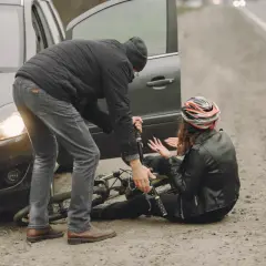 Mężczyzna pomaga kobiecie po wypadku rowerowym. Rozmawiają o odszkodowanie kc.