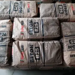 Sztaple worków z betonem B25. Na opakowaniach widnieje informacja o wadze 25kg, co pomaga oszacować, ile cementu na kubik betonu potrzeba do budowy.