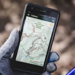 Rękawiczka trzyma smartfon z mapą szlaków rowerowych w Beskidzie Małym. To darmowa aplikacja do jazdy na rowerze, idealna na wyprawę.
