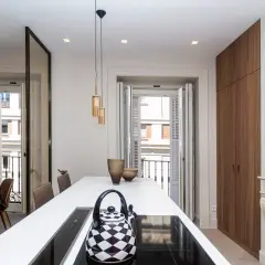 Cocina moderna con isla blanca, tetera a cuadros y vistas a balcón. Un buen lugar para vivir, pero ¿cuánto cuesta un alquiler en Madrid?