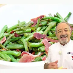 Un chef sonriente presenta un plato de judías verdes salteadas con trozos de jamón.
