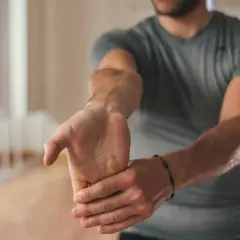Un homme s'étire le poignet, cherchant à soulager une douleur brachial antérieur.